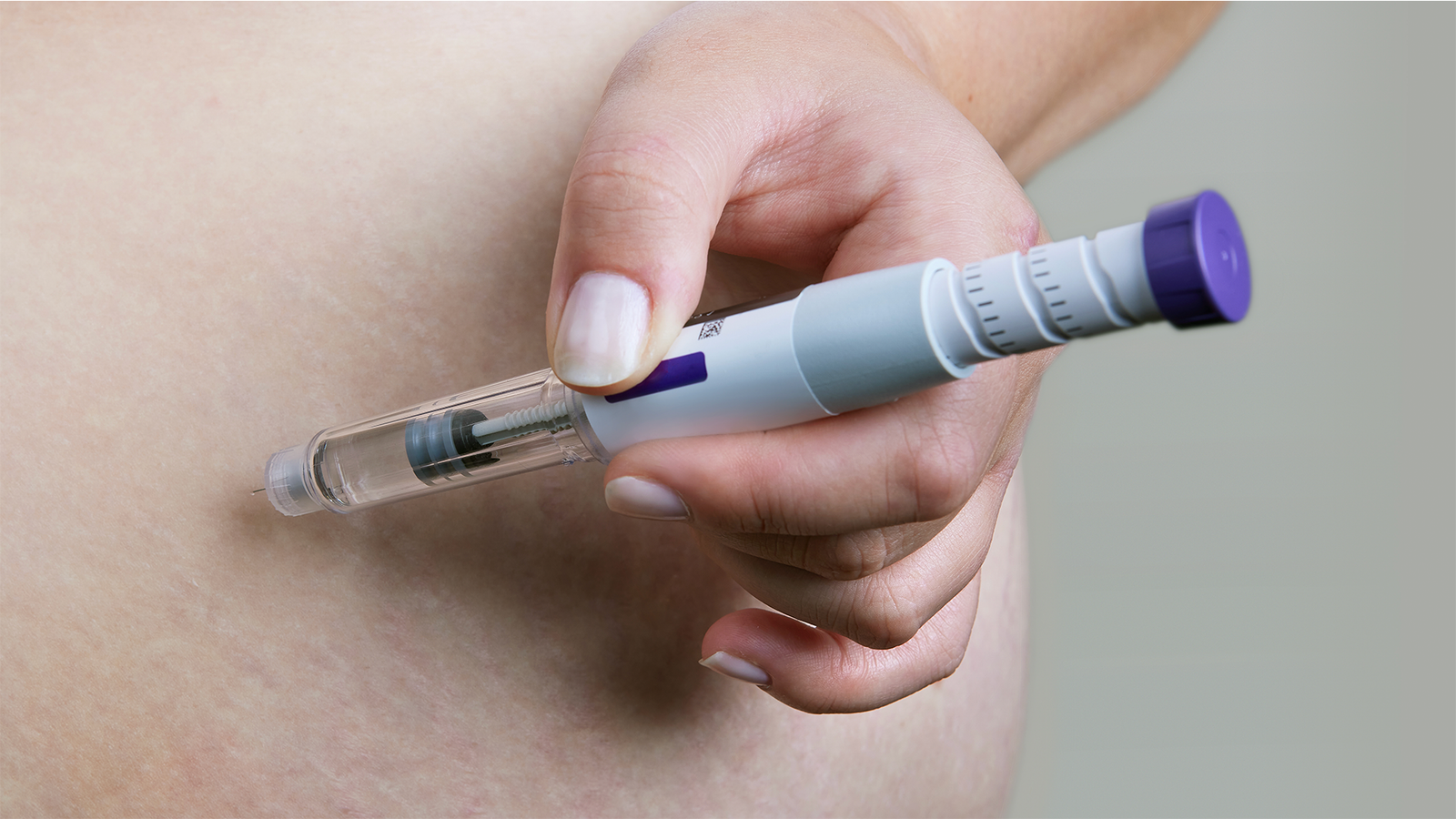 Person administering a peptide injection with an injectable pen, illustrating what are peptides and how peptide therapies are commonly delivered.